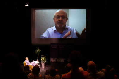 Forfatter Salman Rushdie med live på storskærm på Godsbanen fra sit hjem i samtale med Mads Rosendahl Thomsen.