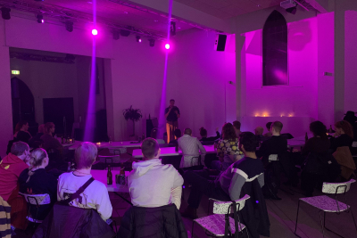 Billede fra arrangement med optrædende og tilhørere.