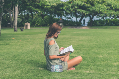 Kvinde, der sidder i en have og læser