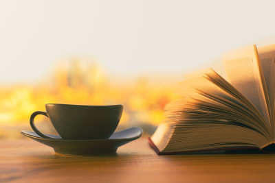Opslået bog ved siden af en kaffekop
