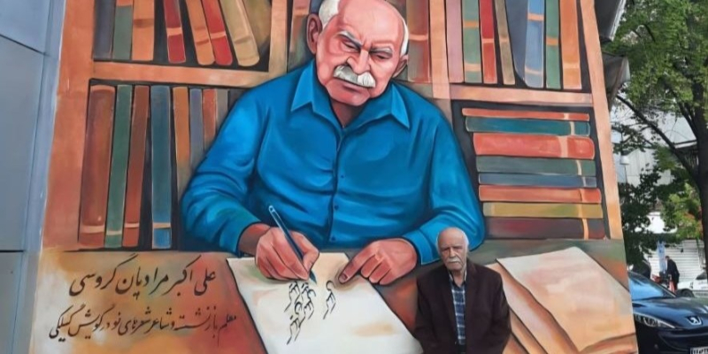 Ali Akbar Moradian Garousi foran vægmaleri af sig selv.