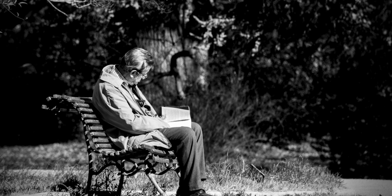 mand, der sidder på en bænk og læser