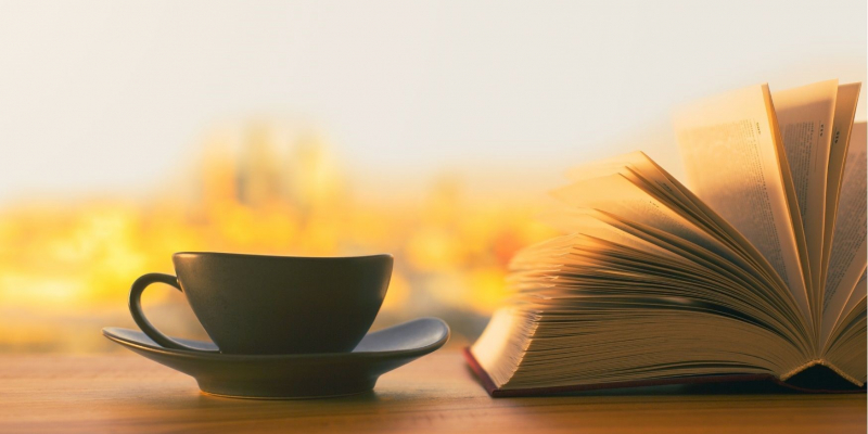 Kaffe kop ved siden af en opslået bog