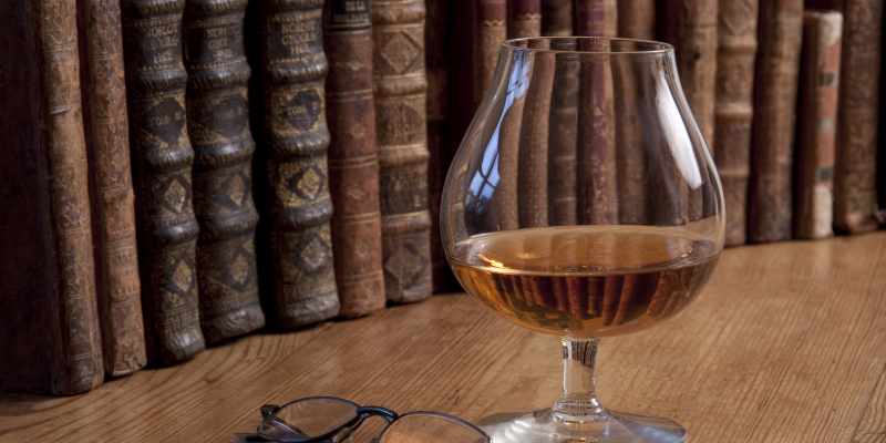 Et par briller, der ligger ved siden af et glas whisky