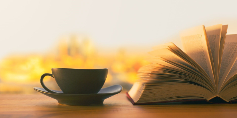 Opslået bog ved siden af kaffekop