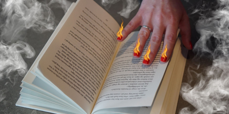 En hånd på en opslået bog, hvor neglene på hånden brænder